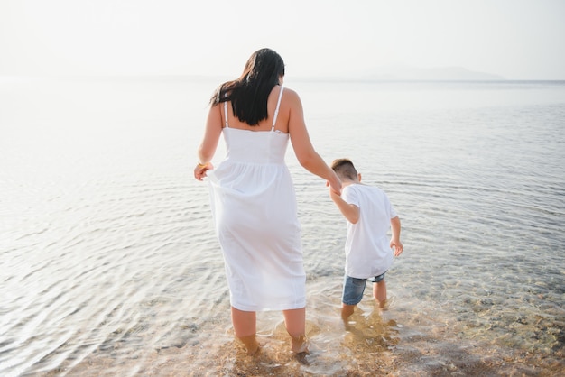 Photo happy mother and son walk along the ocean beach having great family time on vacation on pandawa beach, bali. paradise, travel, vacation concept