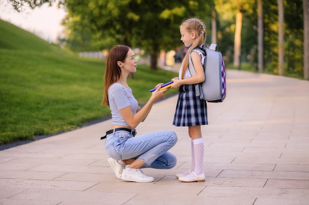 La madre felice porta la piccola studentessa della figlia a scuola