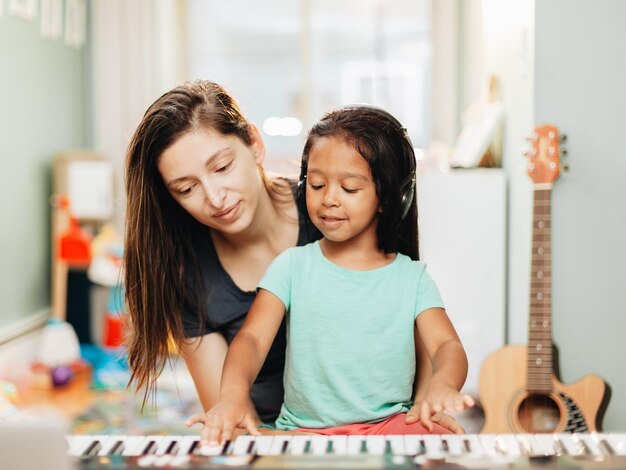 Foto madre felice che insegna pianoforte a sua figlia a casa