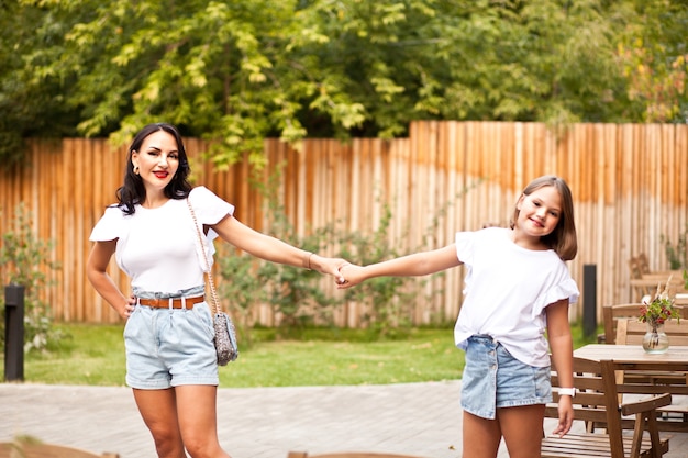 Happy mother and teen doughter standing outdoors in cafe terrace and laughing. family concept