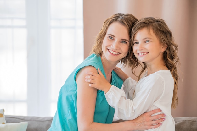 Happy mother and teenage daughter hug each other at home.