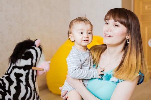 Happy mother with adorable baby boy indoors.