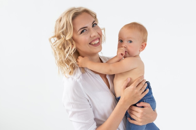 Madre felice con adorabile bambino sul muro bianco