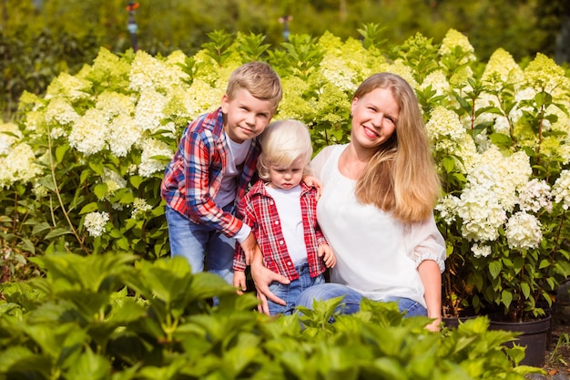 Photo happy mother with cute blonde toddler in her arms smiling to her son standing by lovely family spending time together outdoor at the farm attached parenting concept