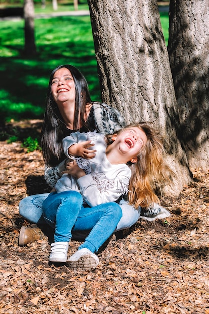 Photo happy mother with cute daughter sitting on field in park