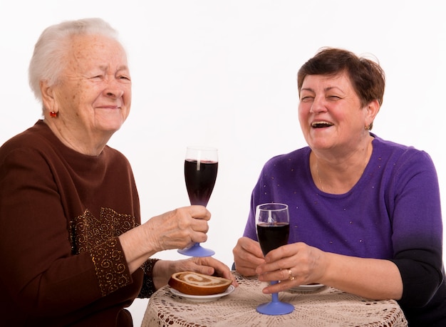 Madre felice con la figlia che beve vino su un bianco