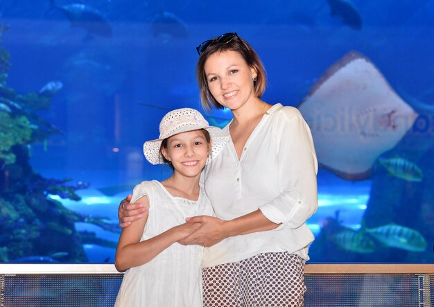 Happy mother with daughter posing aquarium