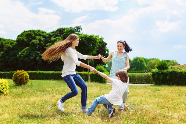 Happy Mother with daughter and son running on grass smiling.