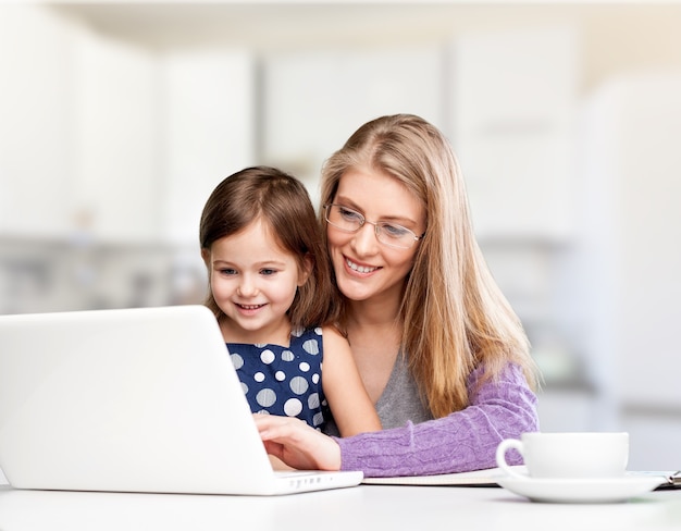 Happy mother with dauther using laptop at home