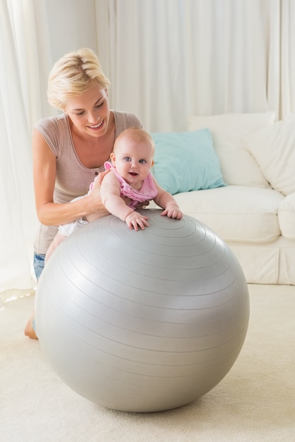 Happy mother with her baby girl in the exercice ball 