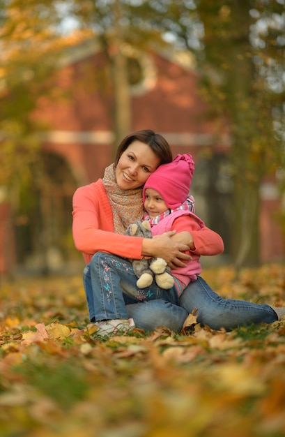 Happy mother with her cute daughter in autumn park