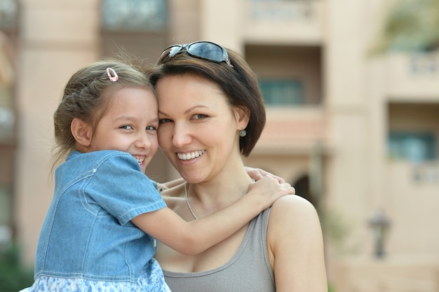 Счастливая мать с дочерью возле отеля летом