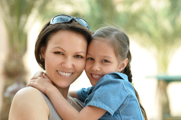 Happy mother with her daughter near hotel at summer