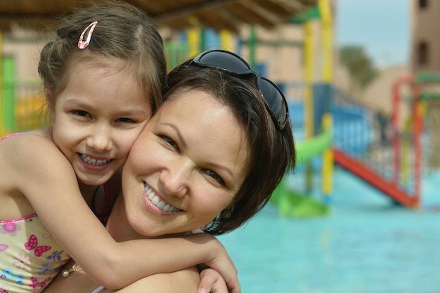 Счастливая мать с дочерью возле бассейна летом