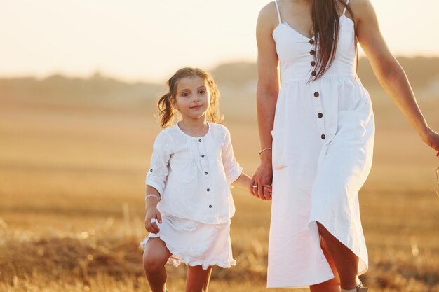 Happy mother with her little daughter spending time together outdoors on the field