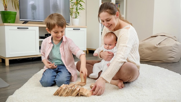 Photo happy mother with her little sons playing games on floor in living room parenting children happiness