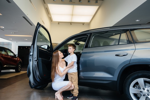 A happy mother with her young son chooses a new car at a car dealership. Buying a car.