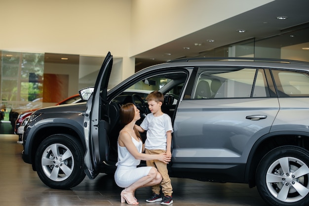 A happy mother with her young son chooses a new car at a car dealership