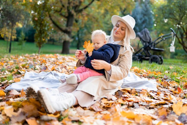 Happy mother with infant playing with leaves