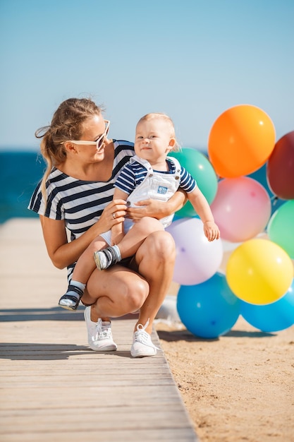 海の近くのビーチで楽しんでいる小さな男の子と幸せな母