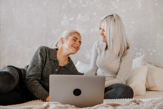 Happy mother with teenager daughter browsing online with application watching video together online shopping chatting or zoom conversation