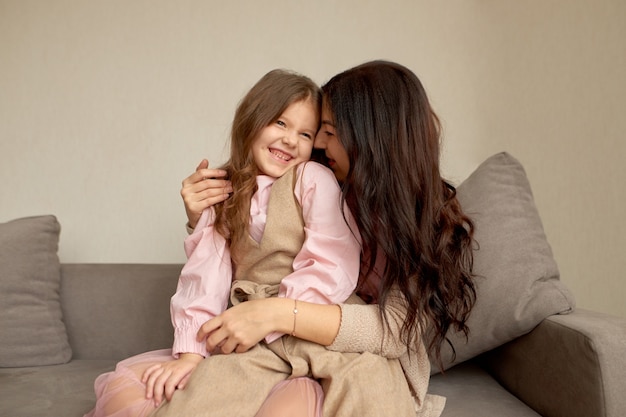 Maternità felice, amore, legame familiare e concetto di amore incondizionato. madre amorevole che si siede sul divano, toccando il naso faccia con adorabile piccola figlia