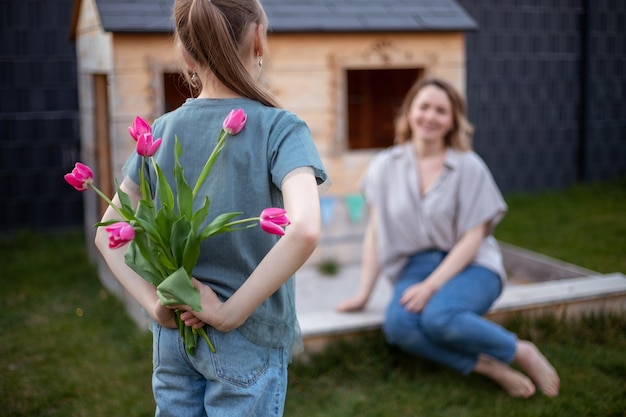 Happy mothers day Child daughter is congratulating mom and giving her flowers tulips Mum and girl smiling and hugging Family holiday and togetherness