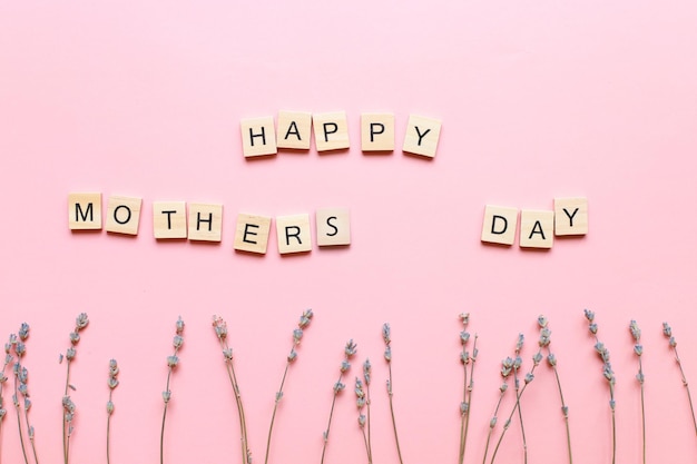 Happy mothers day Een inscriptie gemaakt van letters Flatlay moms day op roze achtergrond
