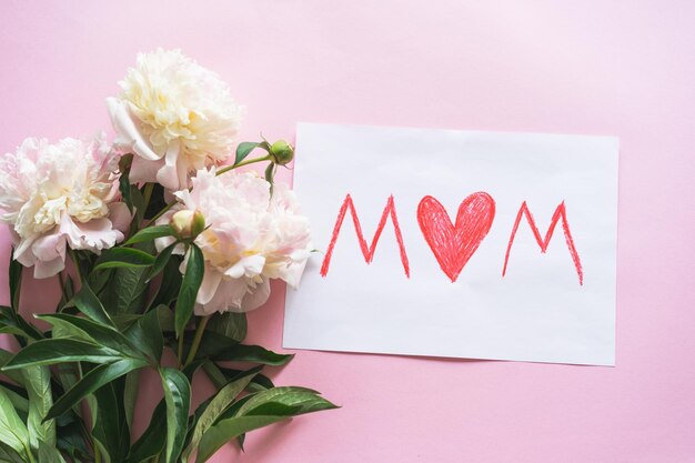 Happy Mothers Day Fresh peonys and postcard for mom on pink background Stylish greeting card Greeting card template with text