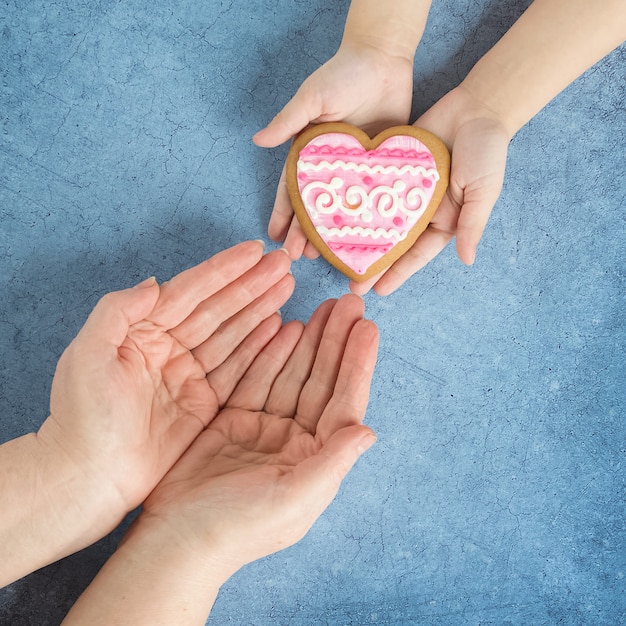 Buona festa della mamma cuore nelle mani di mia figlia e mia madre su sfondo blu