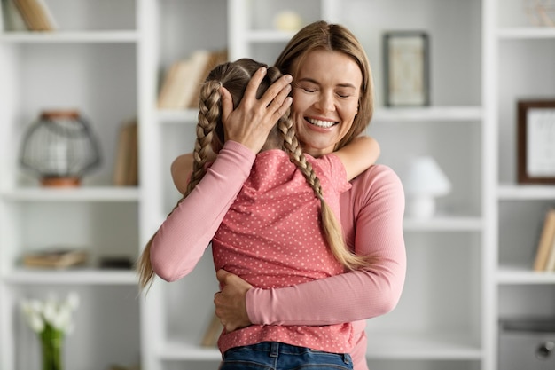 Happy mothers day little girl hugging happy mom at home