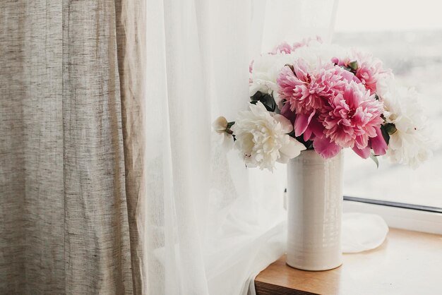 happy mothers day lovely peony bouquet in sunny light on rustic wooden window sill stylish pink and white peonies in vase on wooden background copy space hello spring