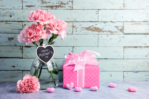 Happy mothers day message on heart wood and pink carnation flower