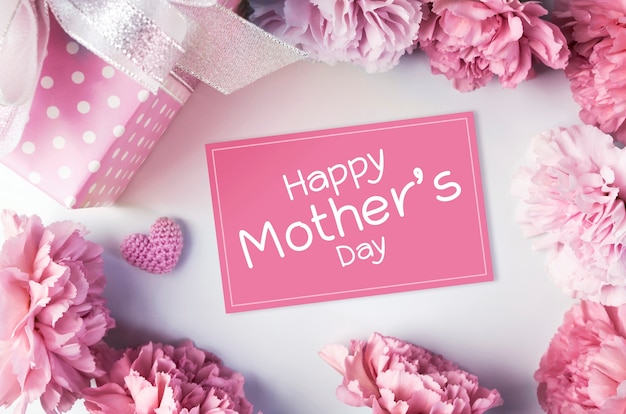 Happy mothers day message on pink paper and carnation flowers and gift box