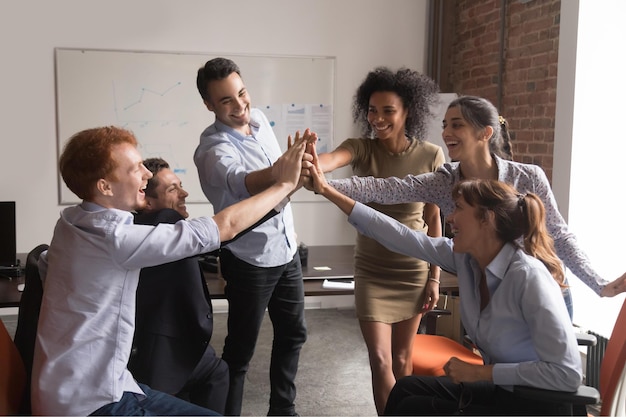 写真 幸せなやる気のある多様なオフィス従業員グループが一緒にハイファイブを与える企業の信頼の概念興奮したビジネスマンは、報酬の成功を祝い、チームビルディングの精神に従事する良いチームワークの結果