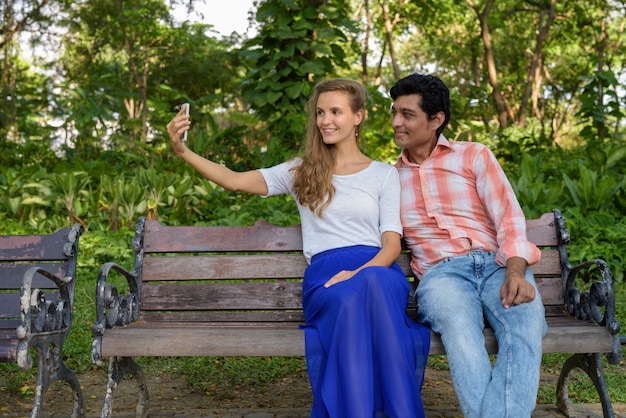 Happy multi ethnic couple smiling while taking selfie picture