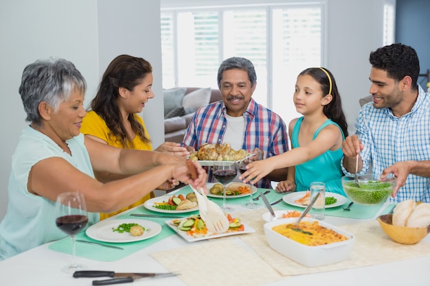 Счастливая семья много поколений имея еду на таблице дома