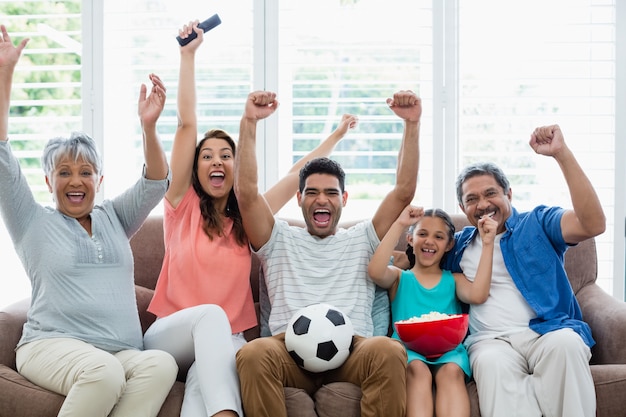 Photo happy multi-generation family watching soccer match on television in living room