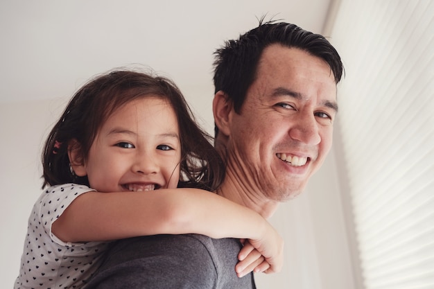 Happy multicultural Asian daughter with her father at home