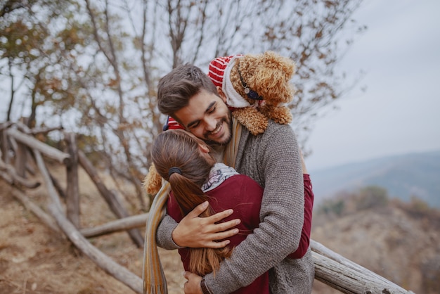 Le coppie multiculturali felici nell'amore hanno vestito abbracciare casuale in natura all'autunno. uomo che ha il cane sulle spalle.