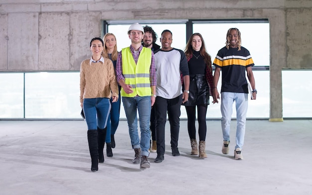 happy multiethnic business team walking through  unfinished startup office during moving in at new building