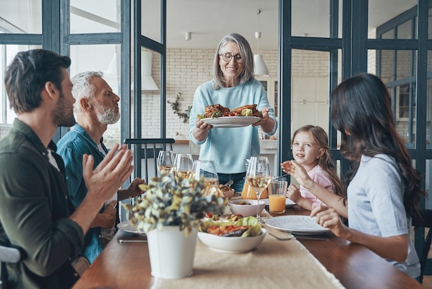 Happy multigeneration family communicating and smiling while having dinner together