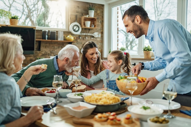 Happy multigeneration family gathering around dining table and having fun during a lunch