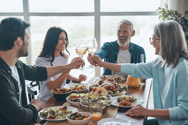 Felice famiglia multigenerazionale che si brinda a vicenda e sorride mentre cena insieme