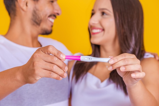 Happy multinational couple celebrating positive pregnancy test result Happy and affectionate joyful couple celebrating motherhood