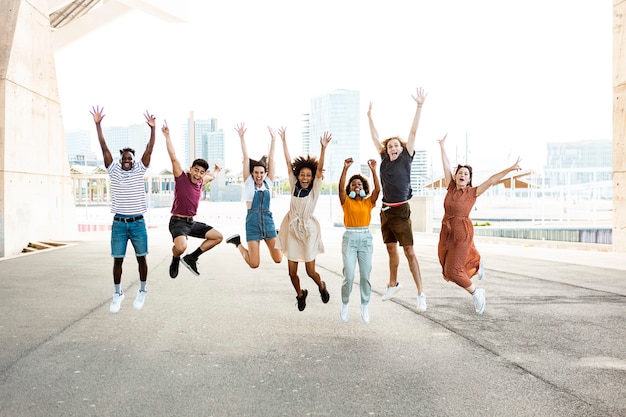 Happy multiracial people jumping together outdoors