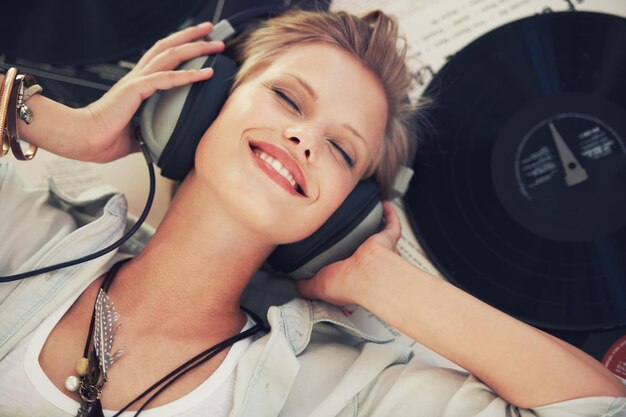 Photo happy music and woman with headphones on floor for streaming subscription audio and radio podcast smile and above of person listening to playlist song and track for relaxing in home with vinyl