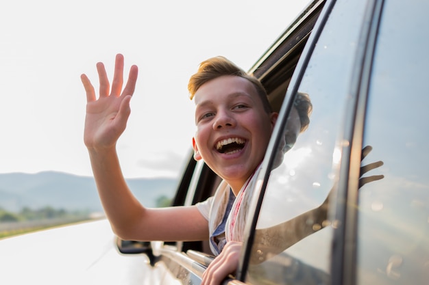 Felice ragazzo musulmano sventolando fuori dal finestrino della macchina