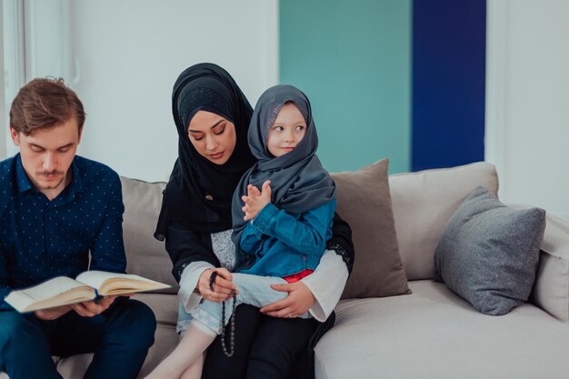 Photo happy muslim family enjoying the holy month of ramadan while praying and reading the quran together in a modern home.