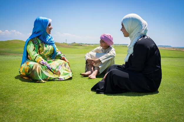 Happy Muslim family on green meadow